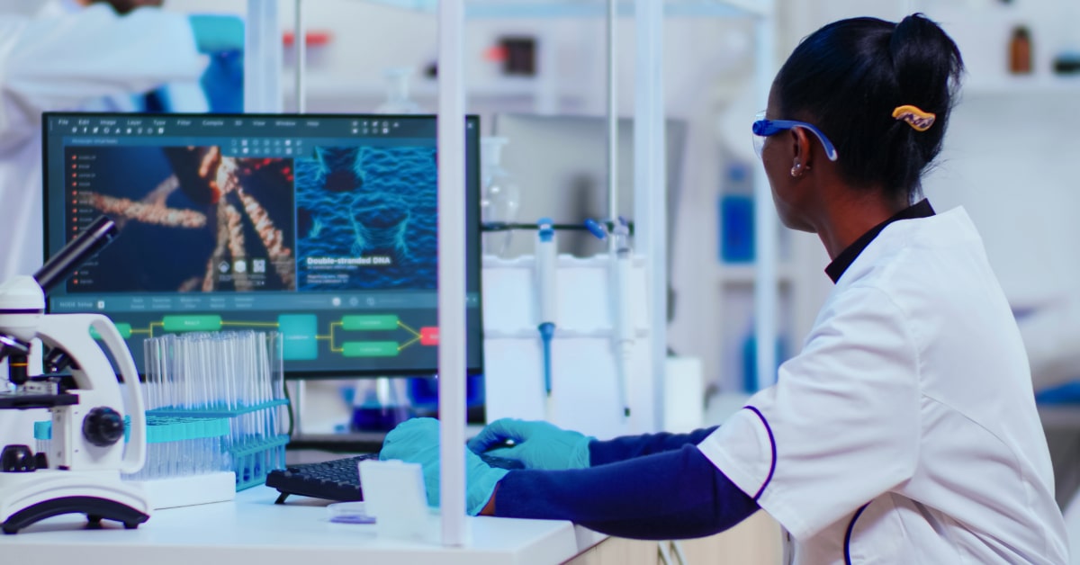 Scientist analyzing genetic data on computer screen in modern laboratory to identify disease risks for precision medicine prevention